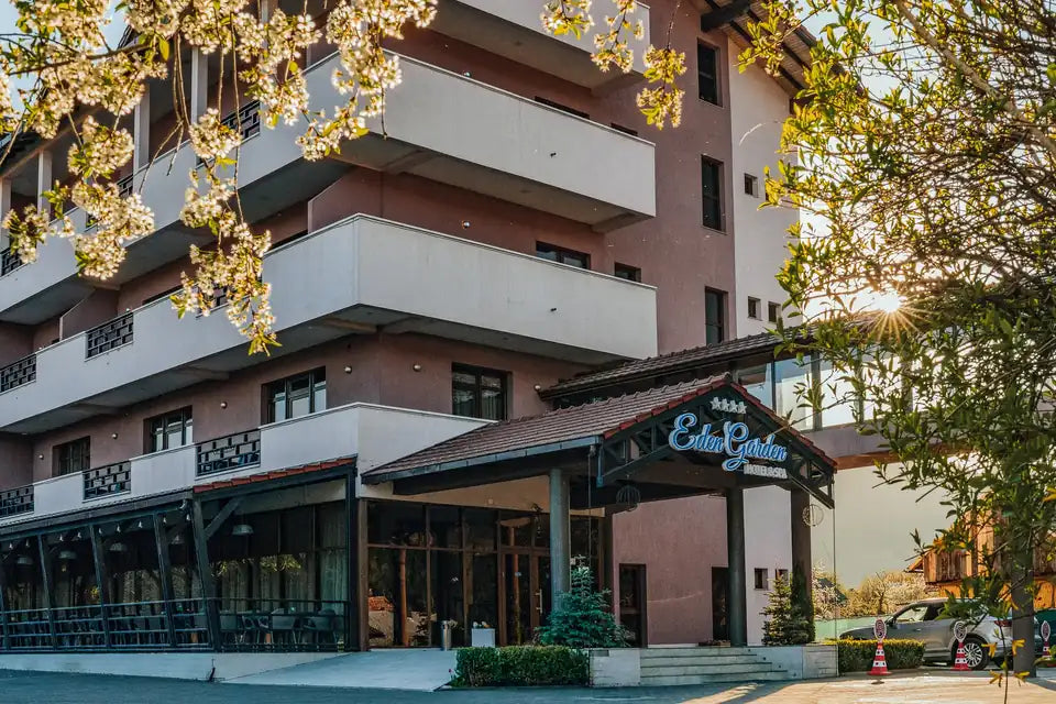 Fațada Hotel Eden Garden & Spa, cu balcoane, intrare acoperită și arbori